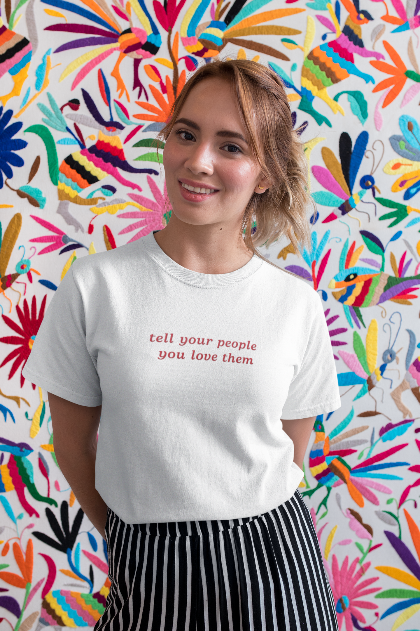 Lady on the beach wearing a white t-shirt with focus on the good embroidered onto it