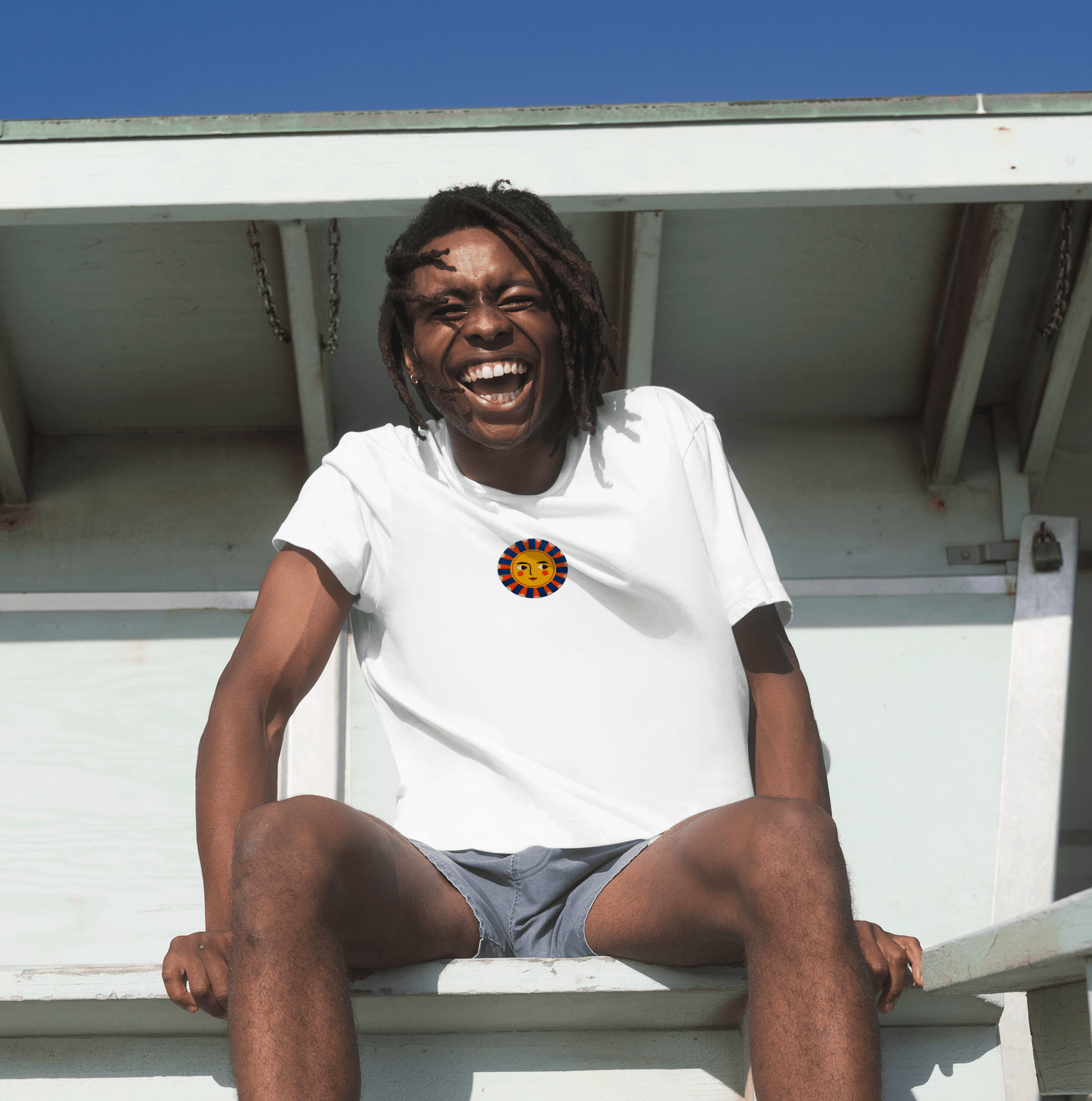 A man with a big smile sitting on a bench wearing a RadiantStitch tee because Life's too short for boring tees!