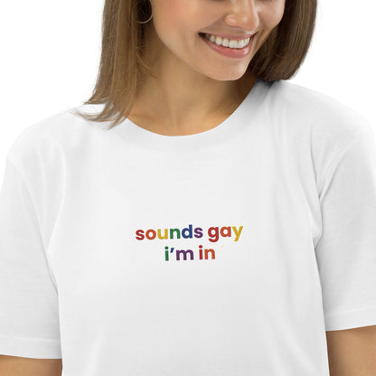 A smiling lady wearing a tshirt "sound gay i'm in" written in bold letters against a vibrant background.