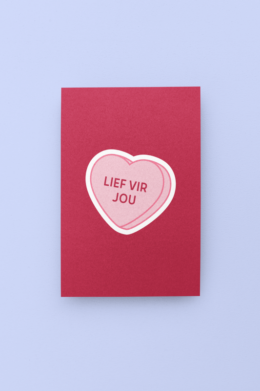 Red card with a pink heart-shaped candy on a light purple background